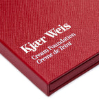 Kjaer Weis Cream Foundation – red textured box, white lettering, white background – makeup
