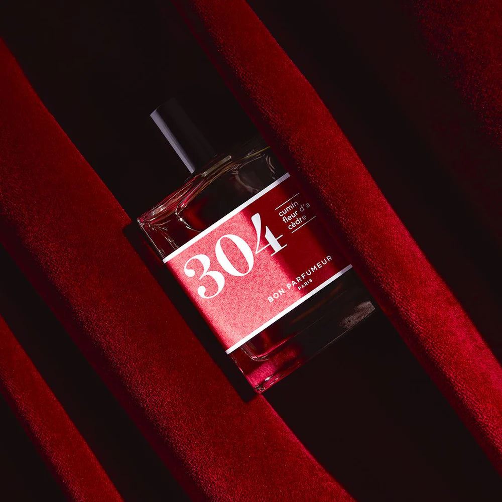 304 Cumin Parfüm – klares Glasfläschchen 100ml, rotes Etikett, schwarzer Verschluss, roter Samthintergrund – Parfum