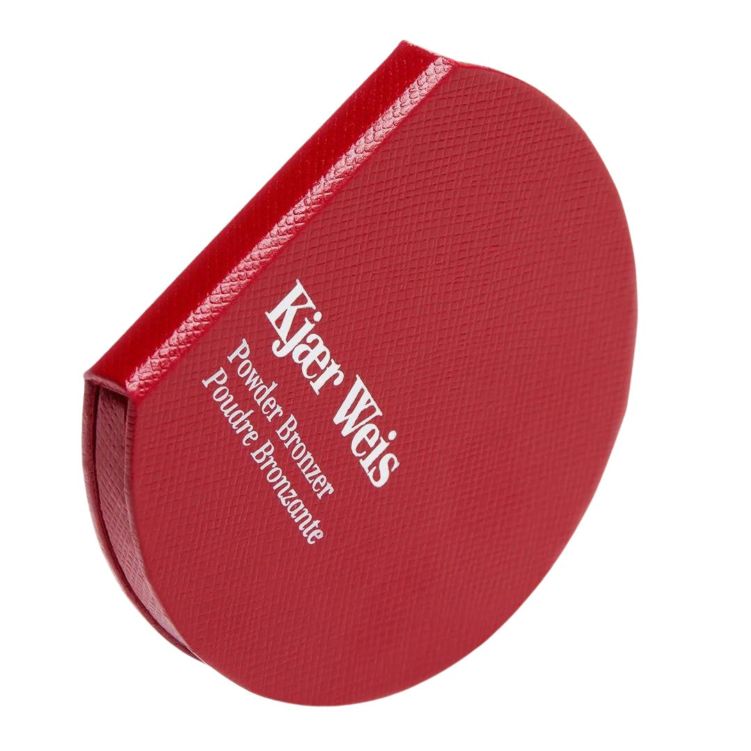 Kjaer Weis Powder Bronzer – runde rote Puderdose, weißer Schriftzug, weißer Hintergrund – Make-up