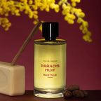 Paradis Nuit Eau de Parfum – klares Glasflakon mit schwarzem Deckel, goldgelbes Parfüm, bordeauxroter Hintergrund – Parfüm