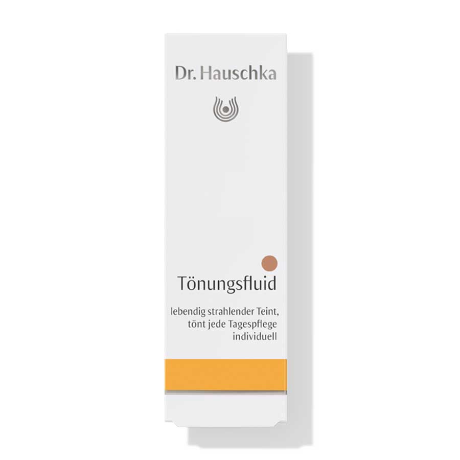 Dr. Hauschka Tönungsfluid – weißes Kartonpaket mit orangefarbenem Streifen, weißer Hintergrund – Gesichtspflege