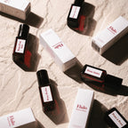 Eläio Peau Parfum-Set – dunkle Glasfläschchen mit schwarzen Kappen, weiße Kartons, beige Hintergrund – Hautparfüm