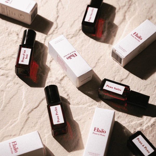 Eläio Peau Parfum-Set – dunkle Glasfläschchen mit schwarzen Kappen, weiße Kartons, beige Hintergrund – Hautparfüm
