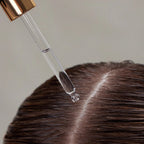 Hair Renew Daily Active Serum – klare Pipette mit roségoldenem Deckel, transparentes Serum auf braunem Haar, neutraler Hintergrund – Haarpflege