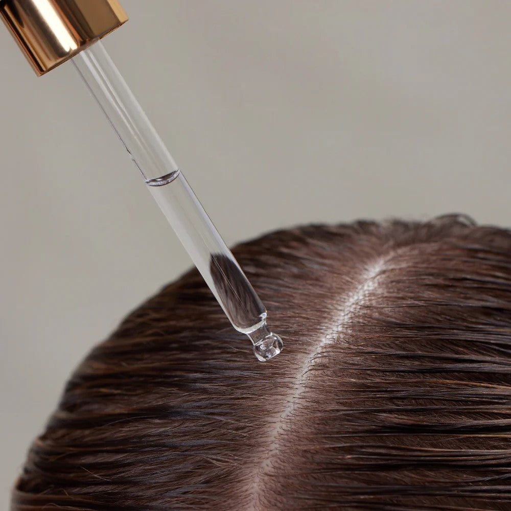 Hair Renew Daily Active Serum – klare Pipette mit roségoldenem Deckel, transparentes Serum auf braunem Haar, neutraler Hintergrund – Haarpflege