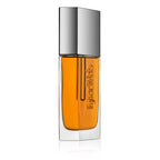 Kjaer Weis The Beautiful Oil – durchsichtige Glasflasche mit orangefarbenem Öl, silberner Kappe, weißem Hintergrund – Hautpflege
