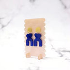 Translucence II – blaue Ohrringe mit gelben Akzenten auf cremefarbenem Display, marmorierter Hintergrund – Schmuck
