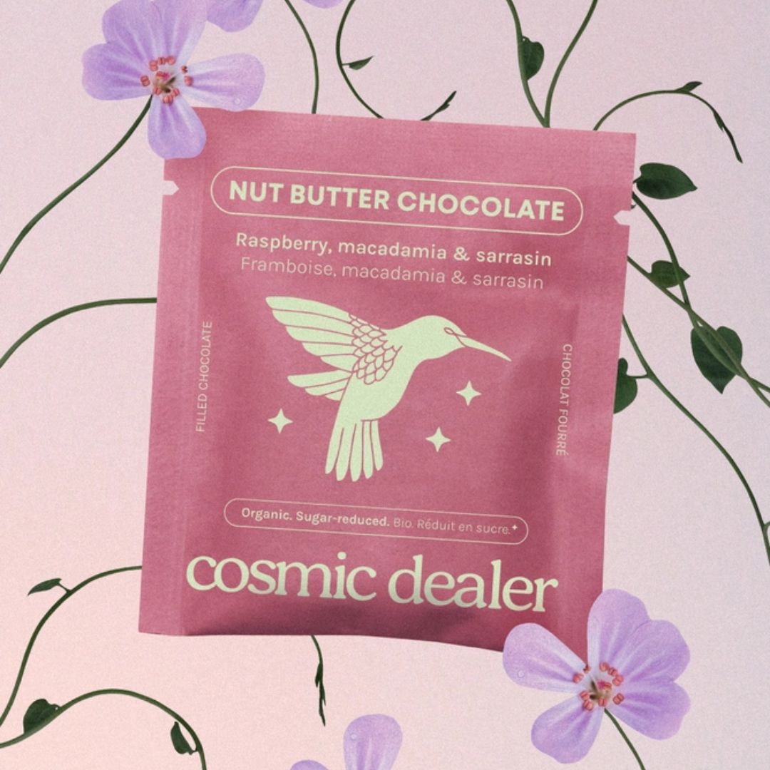Cosmic Dealer Nut Butter Chocolate – pink pouch with hummingbird, raspberry-macadamia flavor, pastel pink background – snack