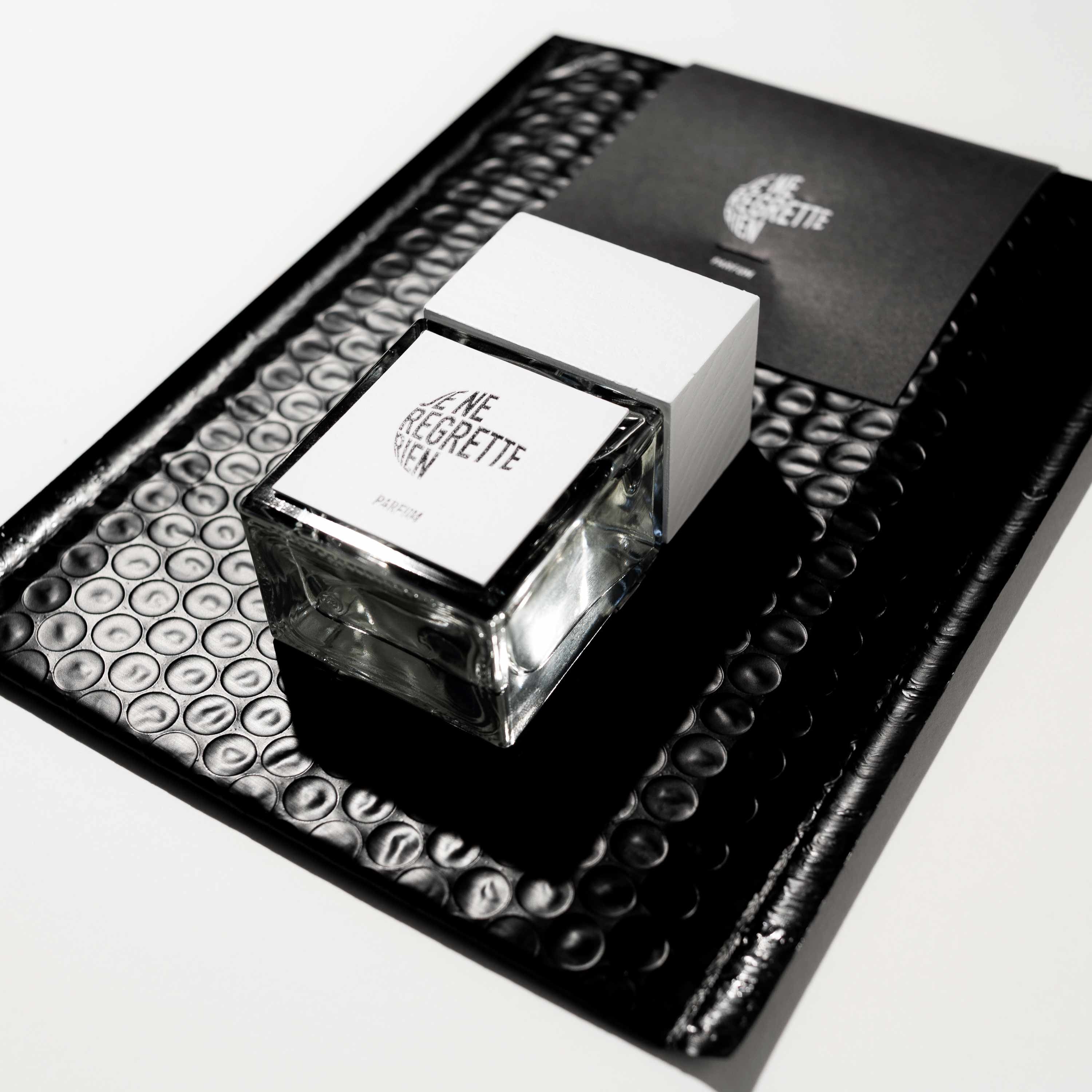 Je Ne Regrette Rien Parfum – square glass bottle with white cap, black background – perfume