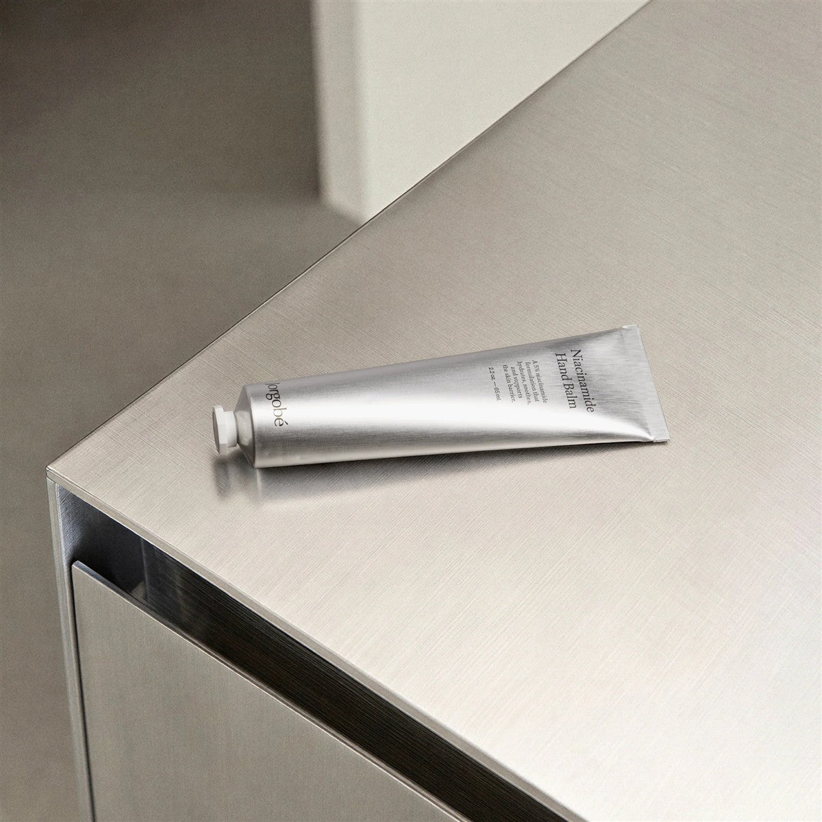 Orgobe Niacinamide Hand Balm – silver tube 60ml, white cap, metallic background – skin care