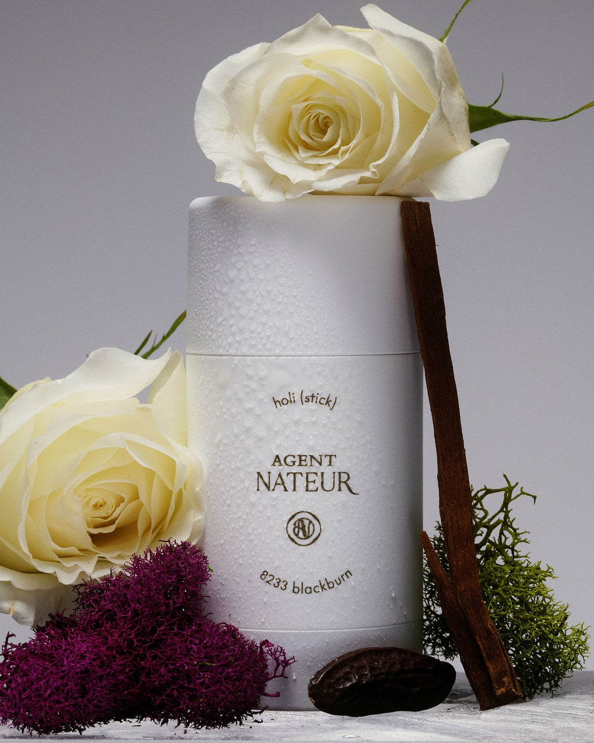 Agent Nateur Holi (stick) stick in white packaging, decorated with white roses, moss and a cocoa bean.