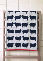 Sheep Organic Cotton Beach Towel with sheep pattern, grey-black, red border, on radiator – beach towel