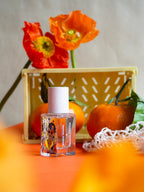 Warni Warni Eau de Parfum – klares Glasfläschchen mit farbigem Etikett, rosafarbener Sprühkopf, orangefarbener Hintergrund – Parfüm