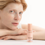 MÁDARA SOS Hydra Repair Intensive Serum in einer 30-ml-Flasche mit pfirsichfarbenem Verschluss vor einer Person.
