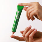Mádara PDRN Algae Shot 7-in-1 Serum in a green tube, product in use with a texture swatch on a finger.
