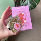She Woke Up and Conquered the World Green Tea Sachets – purple box, clear tea bags with red design, green background – wellness