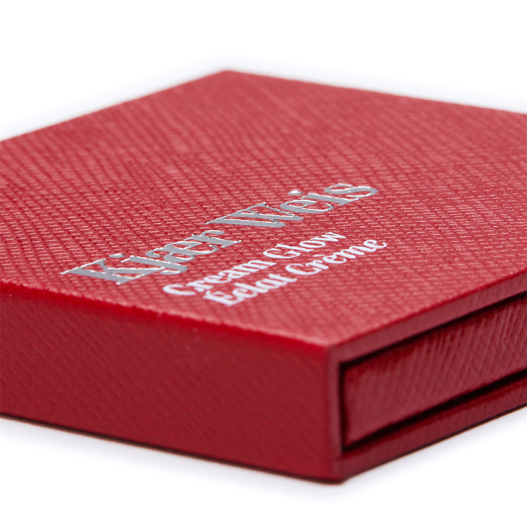 Kjaer Weis Cream Glow – rote Texturbox mit silberner Schrift, weißem Hintergrund – Hautpflege