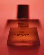 Pause Eau de Parfum – 50ml glass bottle with black cap, red background – perfume