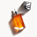 The Beautiful Oil – transparente Glasflasche mit Tropfer, goldfarbenes Öl, weißer Hintergrund – Hautpflege