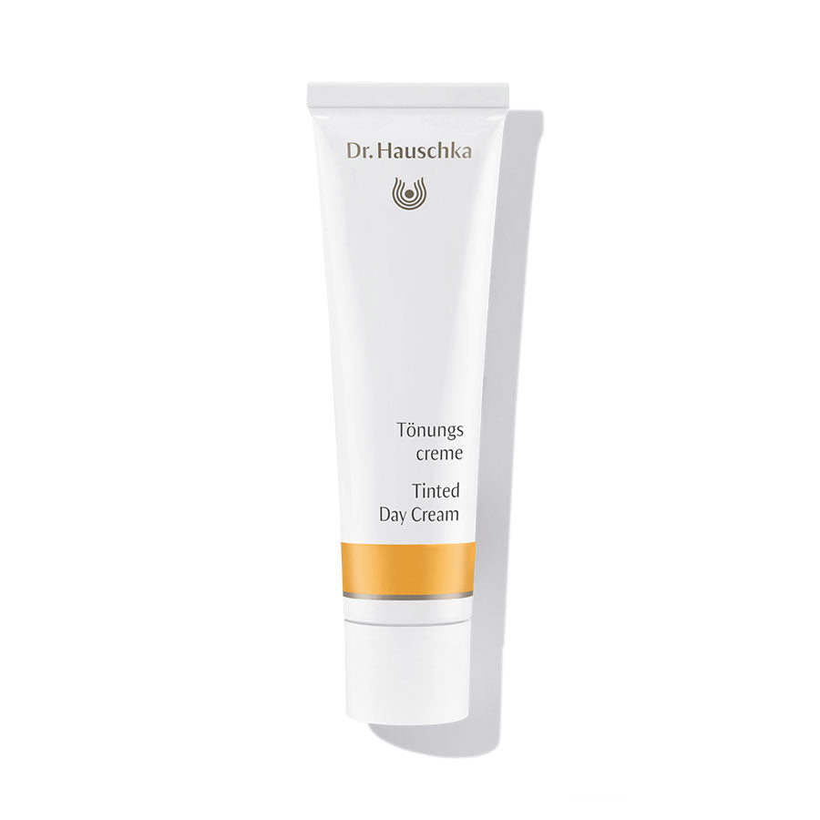 Dr. Hauschka Tönungscreme – weiße Tube mit orangefarbenem Streifen, weißem Deckel, weißem Hintergrund – Gesichtspflege