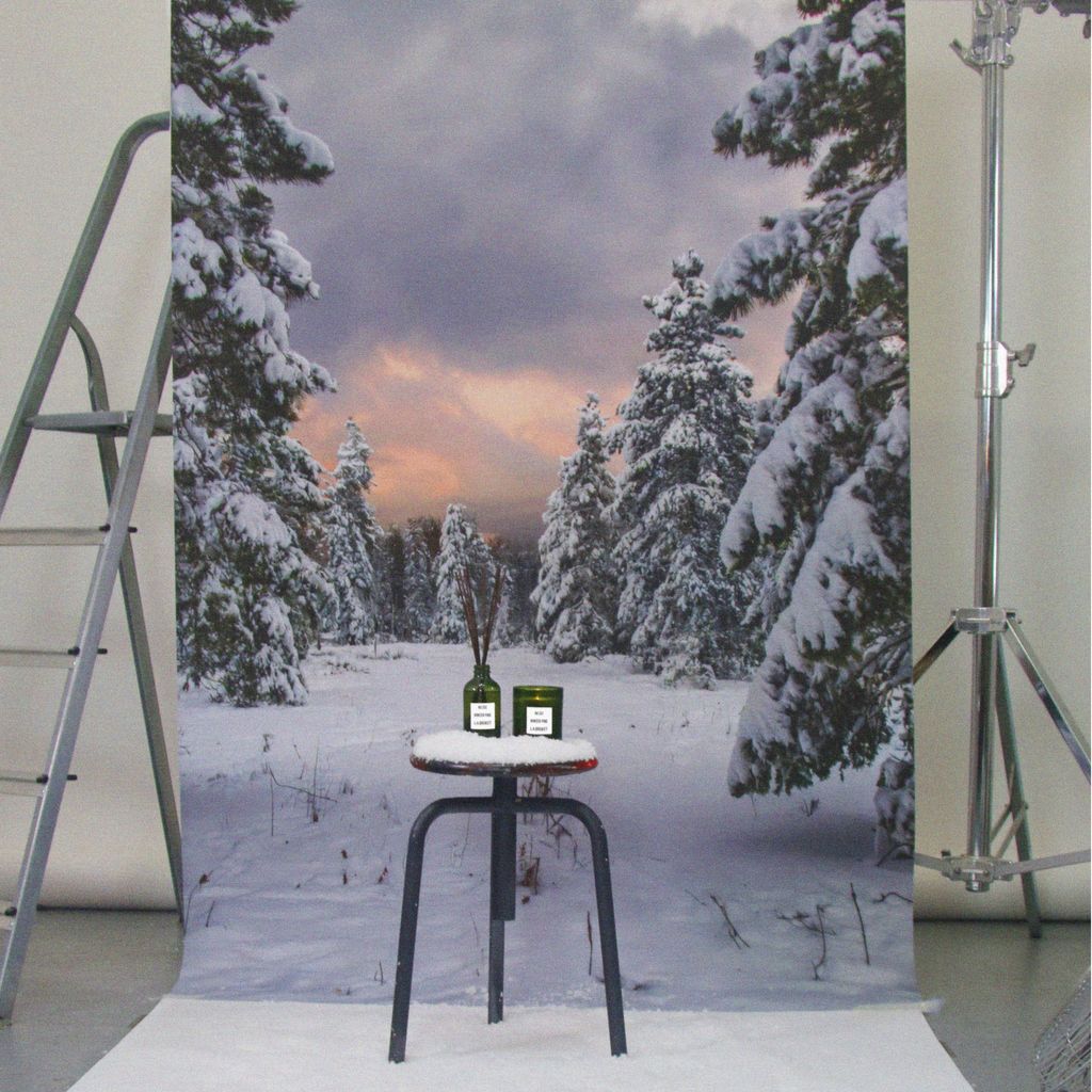 No. 331 Kerze Winter Pine – grüne Glasdose, weißes Etikett, auf schwarzem Hocker vor verschneitem Wald – Duftkerze