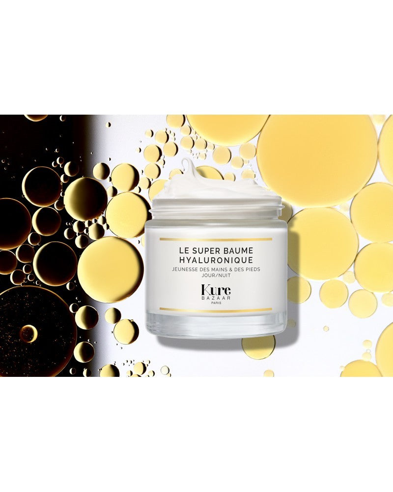 Kure Bazaar Le Super Baume Hyaluronique – weißer Glasbehälter, goldene Akzente, cremige Textur, Hintergrund mit goldenen Öltropfen – Hautpflege