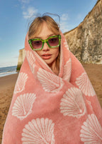 Shells Organic Cotton Bath Towel – pink with white shell patterns, worn at the beach – beach accessories