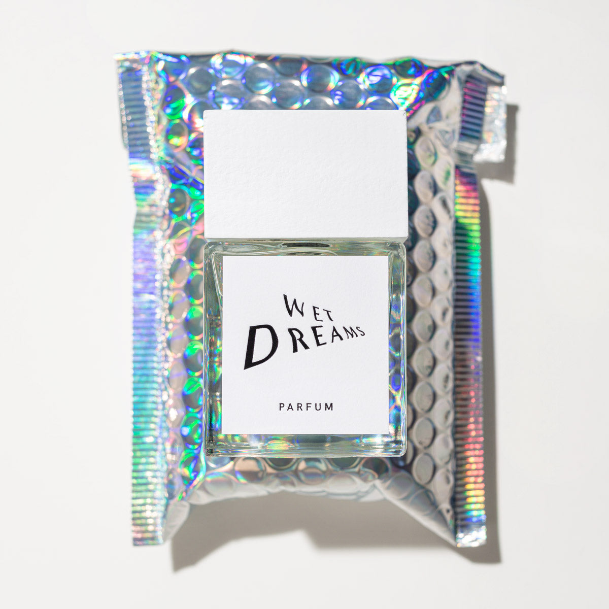 Wet Dreams Parfum – klares Glasfläschchen mit weißem Deckel, holografischem Hintergrund – Parfüm