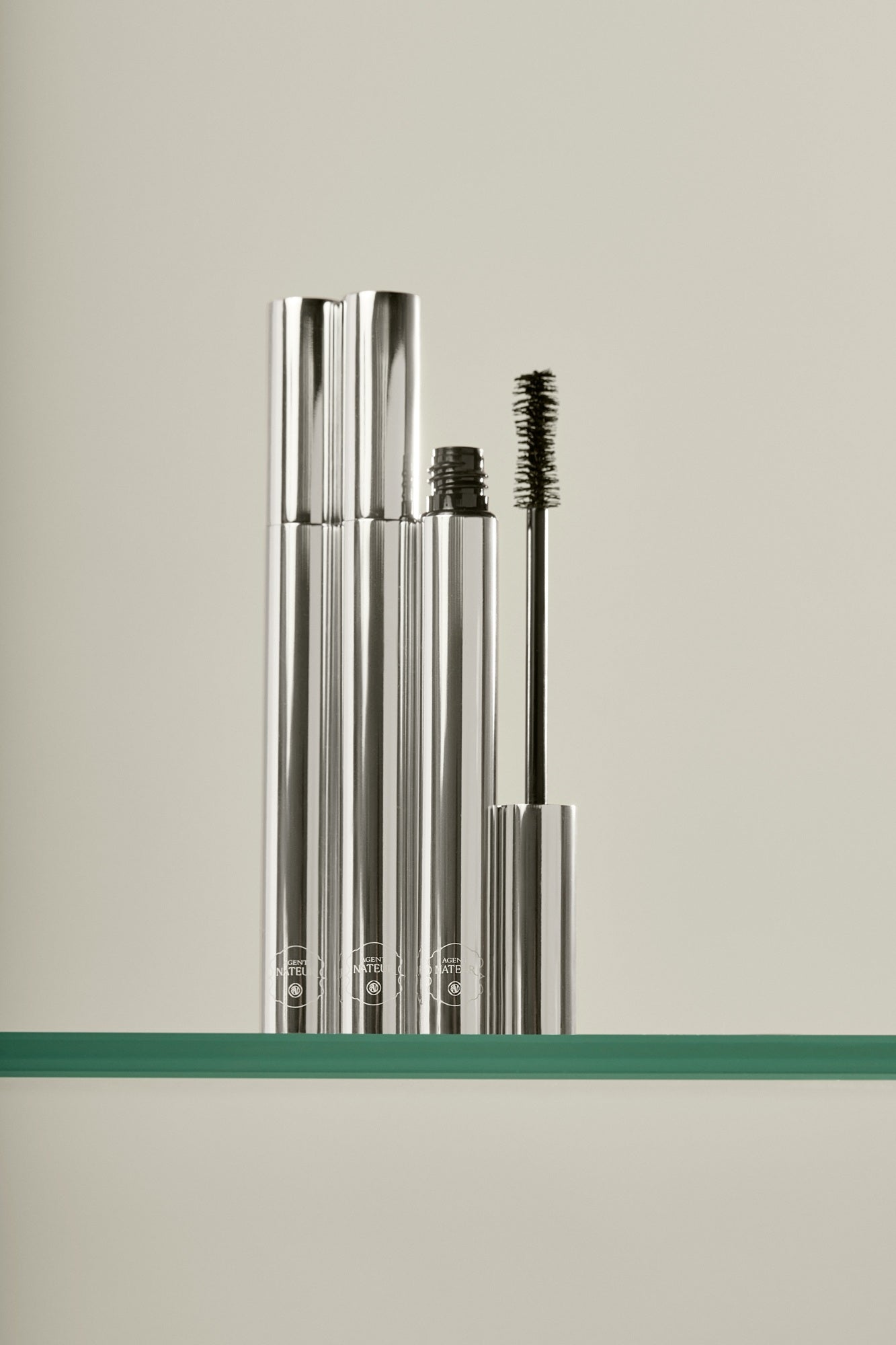 Holi(lash) Growth Mascara – silberne Tube mit geöffnetem Deckel, Wimpernbürste, cremefarbener Hintergrund – Wimpernpflege