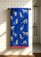 Snow Leopard Bio-Baumwoll-Badelaken mit Leopardenmuster, blau mit rosafarbenem Saum, hängt an Halter – Badetuch