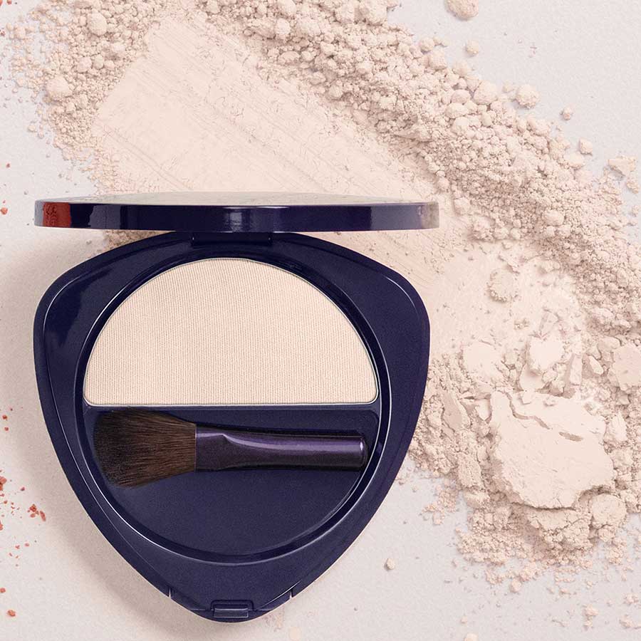 Highlighter in dunkelblauer Dose mit Pinsel, cremefarbener Puder, weißem Hintergrund – Make-up