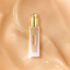 Le Rouge Français Le Fluide de Teint – cremefarbene Flasche mit goldener Pumpe, beige Hintergrund – Make-up