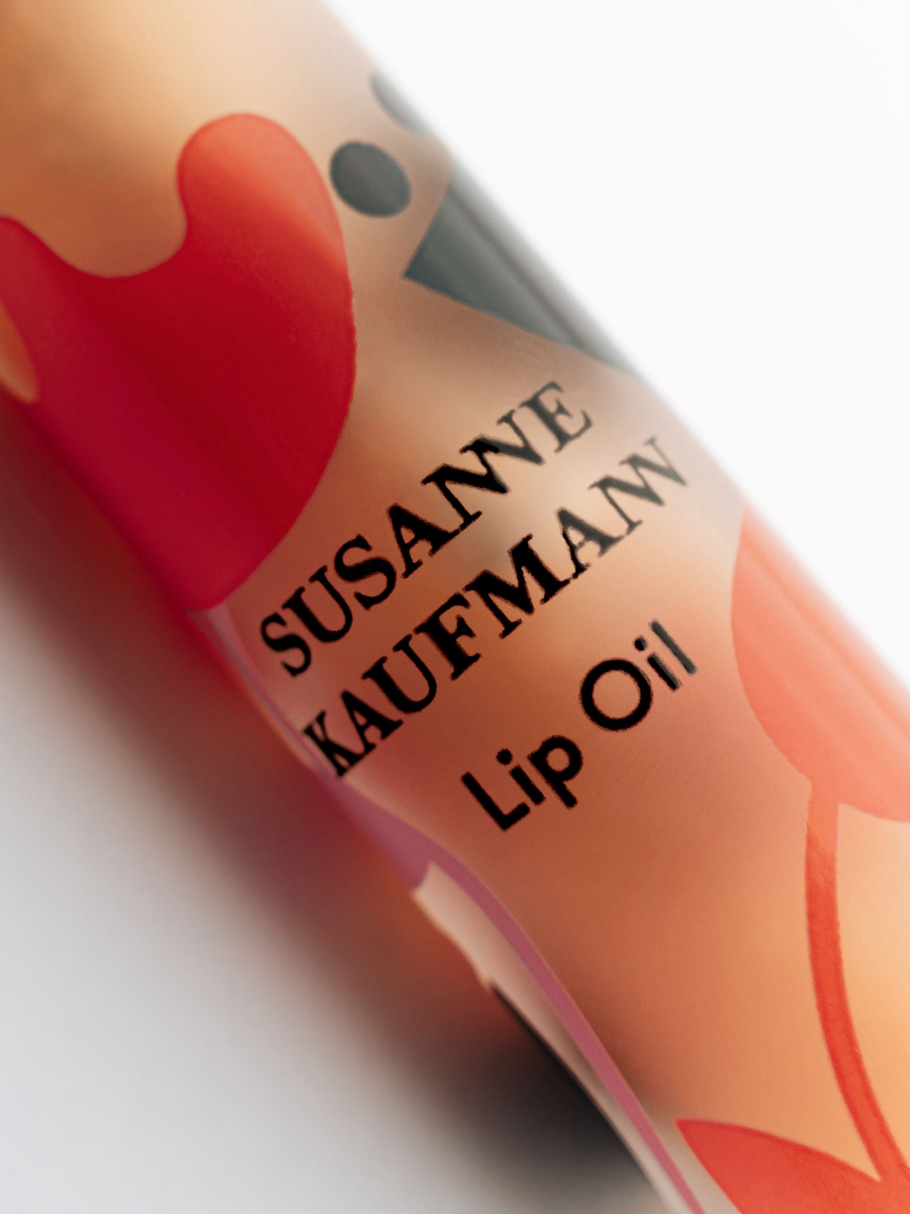 Susanne Kaufman Lip Oil Roll On with red patterns on a white background, lip care