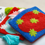 Clutch Galaxy Red, zwei perlenbestickte Taschen in Blau und Rot mit grünen Sternen und Quasten auf weißem Untergrund.
