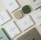 Tenth Muse Solid Perfumes: Mehrere weiße Verpackungen und zwei quadratische Tiegel in Beige und Olivgrün.