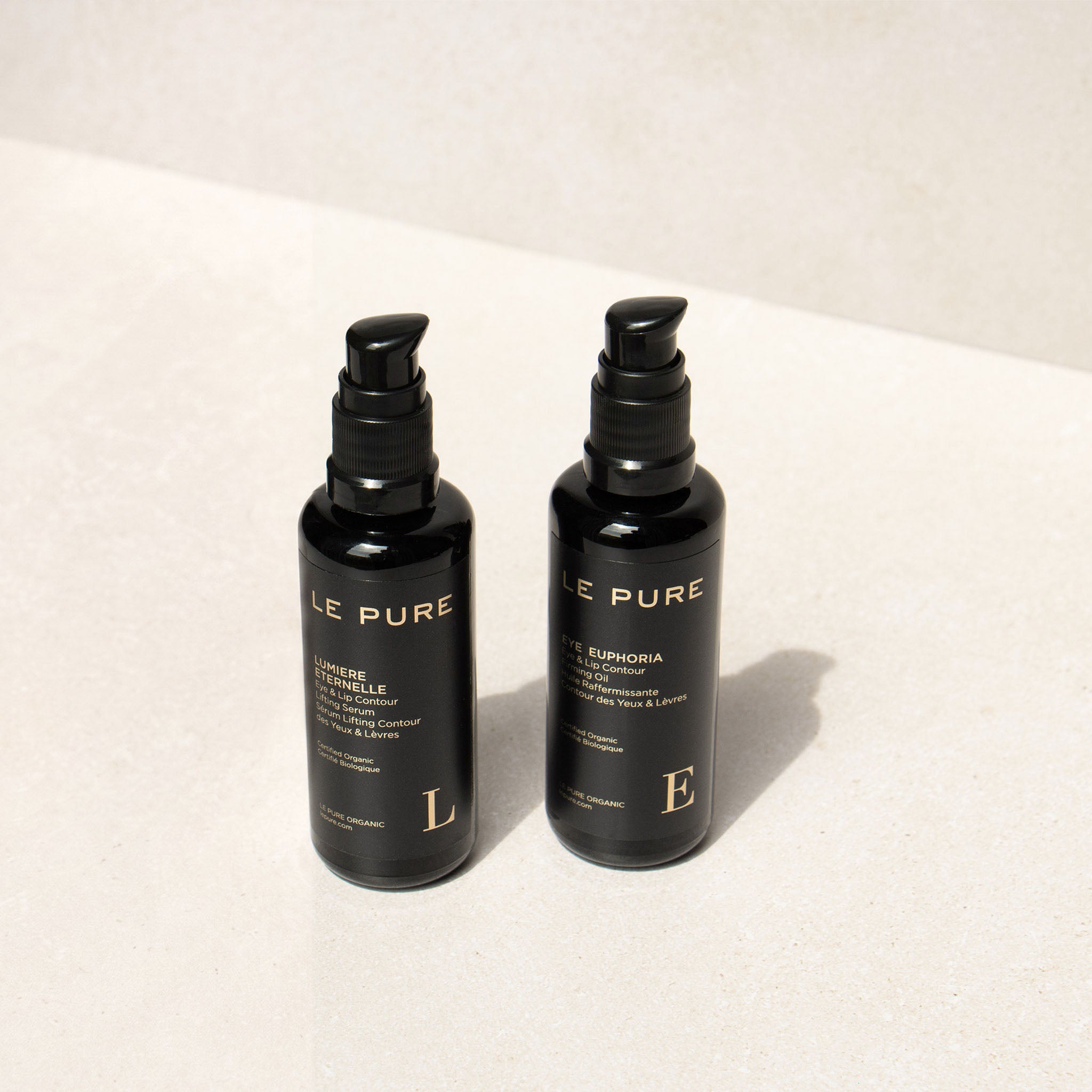 Le Pure E&l the Eye Set: zwei schwarze Flaschen mit Pumpaufsatz auf hellem Hintergrund, Augenpflege.