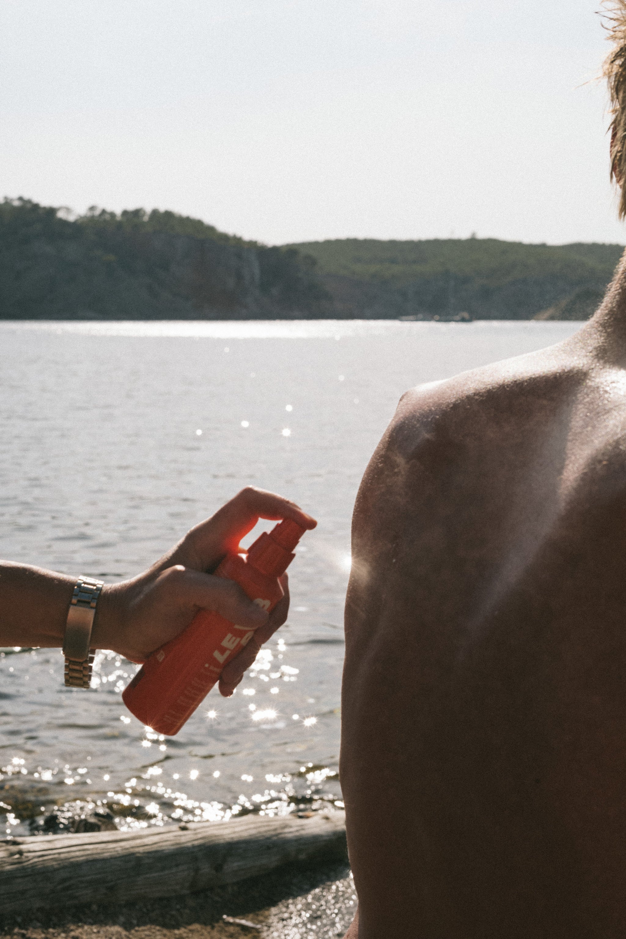 Orange spray bottle with nozzle for Sunscreen Mist SPF 50 Body skin care by the sea.