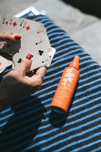 Orange LE RJ Sunscreen Mist SPF 50 spray bottle with cap on a blue and white towel, body sun care.