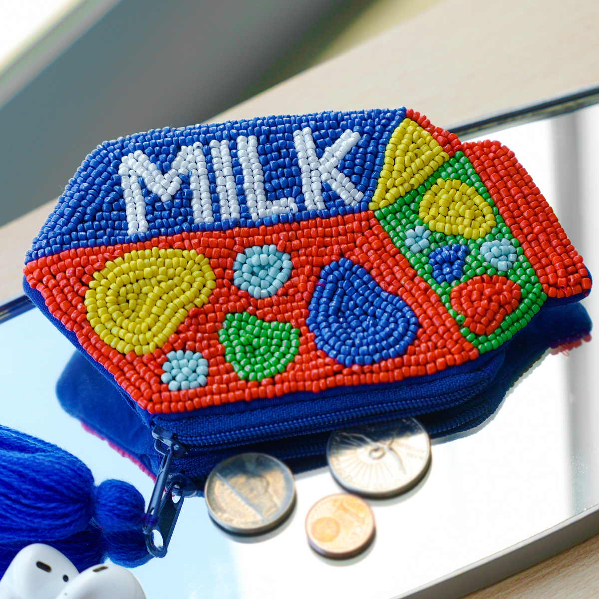 Small Carton of Milk Clutch, eine perlenbestickte kleine Tasche in Form eines Milchkartons auf einem Spiegel mit Münzen.