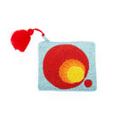 Clutch Pequeño Degradado, a small light blue beaded clutch featuring a red and yellow circular design and a red tassel.