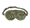 Le Palmier sleep mask made of green fabric with a palm tree pattern on a white background.