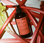 L:A Bruket No. 339 Hand & Body Wash, brown bottle with rhubarb red label, surrounded by rhubarbs