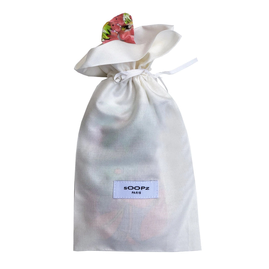 Le Flora mask in a white fabric pouch with a drawstring.