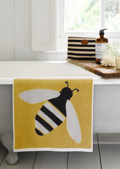 Buzzy Bee Bio-Baumwollwaschlappen – gelb mit Bienenmotiv, weißer Rand, auf Badewanne – Hautpflege