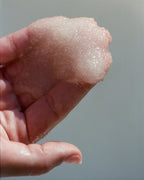 No. 297 Sea Salt Scrub Lemongrass – rosafarbener Peeling in der Hand, grauer Hintergrund – Körperpflege