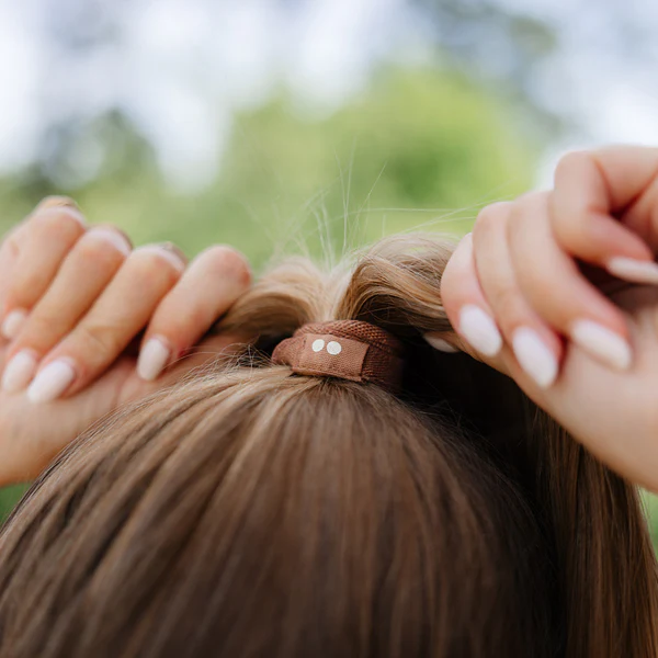 Plastic Free Flat Hair Ties Earth Tints – brauner Haargummi im Einsatz, natürlicher Hintergrund – Haarpflege