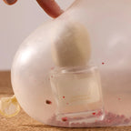 Radical Softness Eau de Parfum – clear glass bottle with cream spray nozzle, pink background – perfume