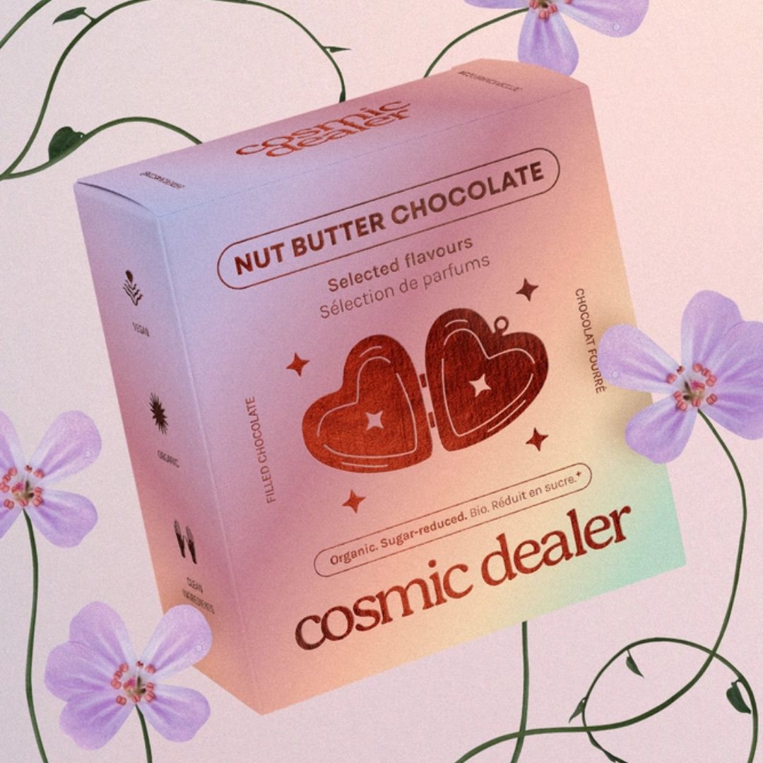 Cosmic Dealer Nut Butter Chocolate – farbverlaufende Kartonverpackung mit Herz-Motiv, lila Blumenhintergrund – Süßigkeiten