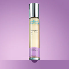 The Organic Pharmacy Brightening Plus Serum in einer Flasche mit Silberverschluss vor violettem Hintergrund, Hautpflege Moodbild