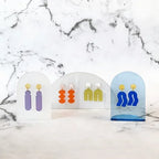 Spectral Blue Ohrringe – blaue Acryl-Form mit goldener Fassung, weißer Marmorhintergrund – Schmuck